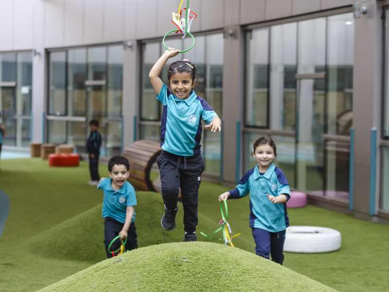 A child leaping with ribbons in the Early Years garden