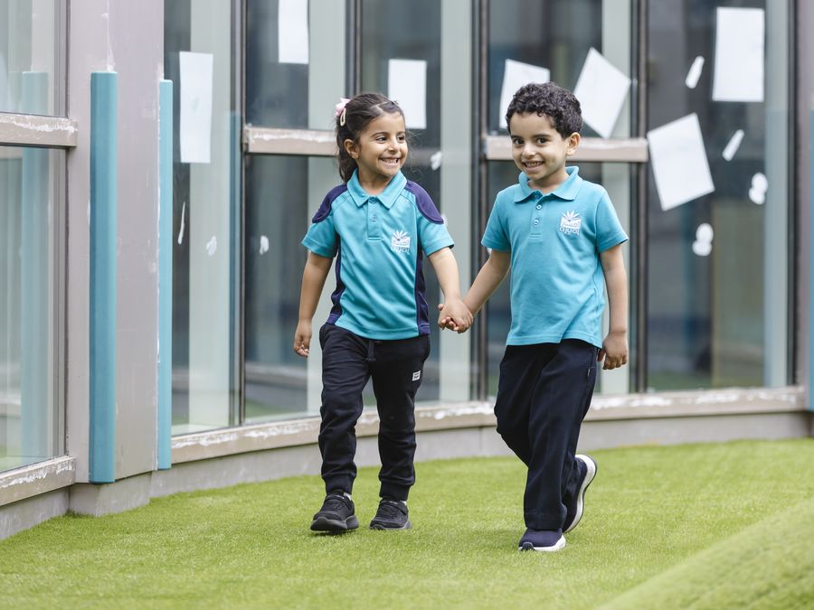Two Early Years children running together at Ajyal